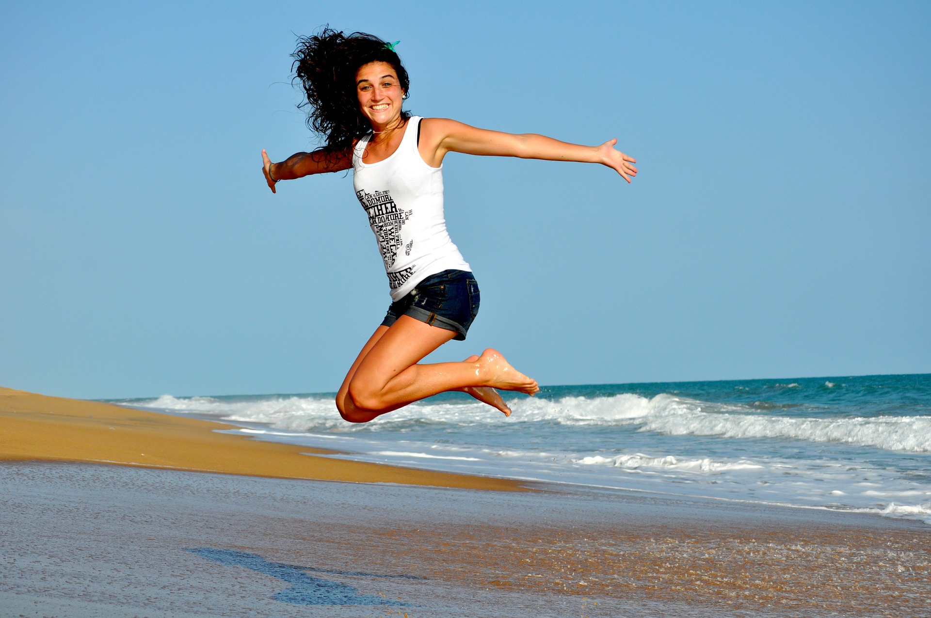 a girl jumping on a sea beach